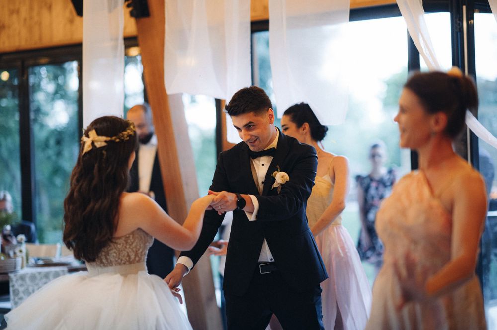 Wedding party dancing together in rustic venue decorated with white draping.