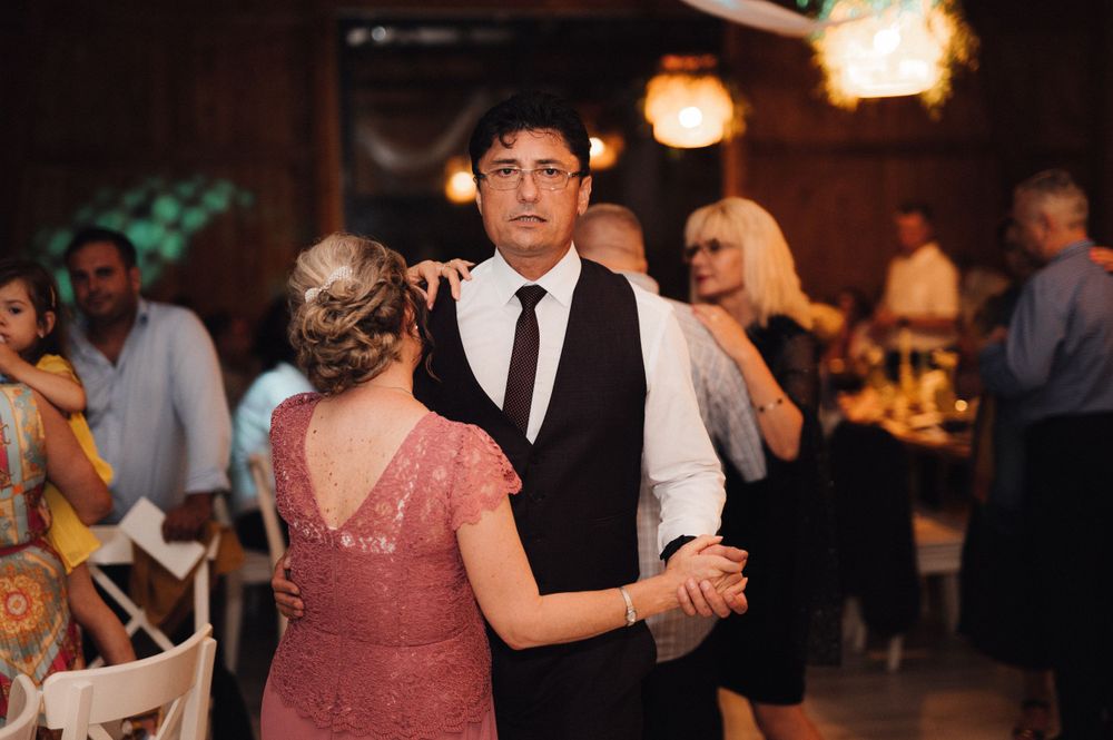 Wedding guests dance together on a dimly lit dance floor during the reception celebration.