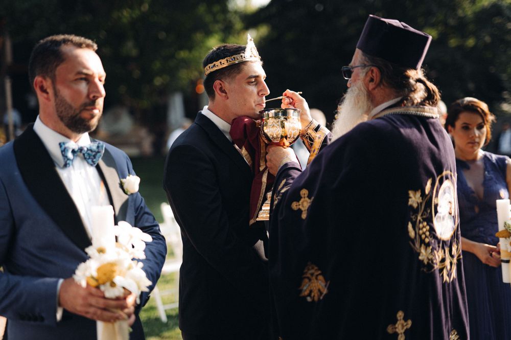 Wedding participants in formal attire during a traditional Orthodox ceremony outdoors.