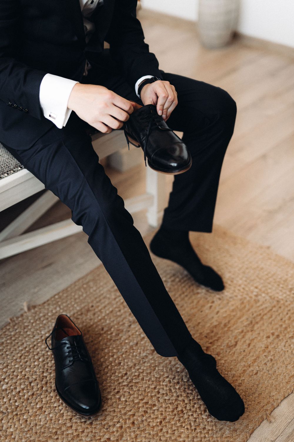 Close-up of formal black dress shoes being put on with a tuxedo.