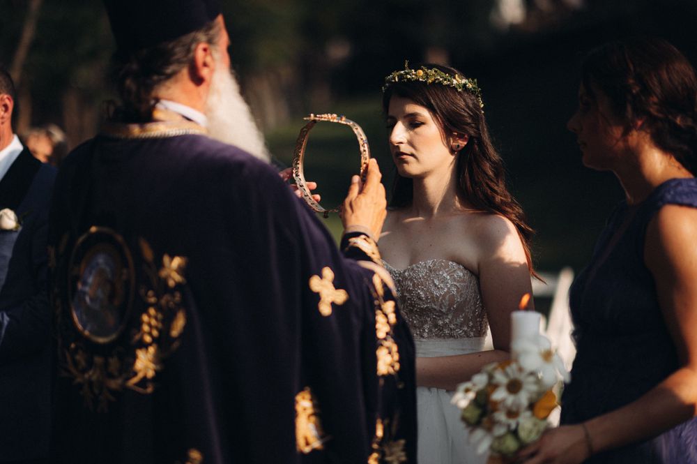 An Orthodox priest officiates a wedding ceremony while holding ceremonial items.