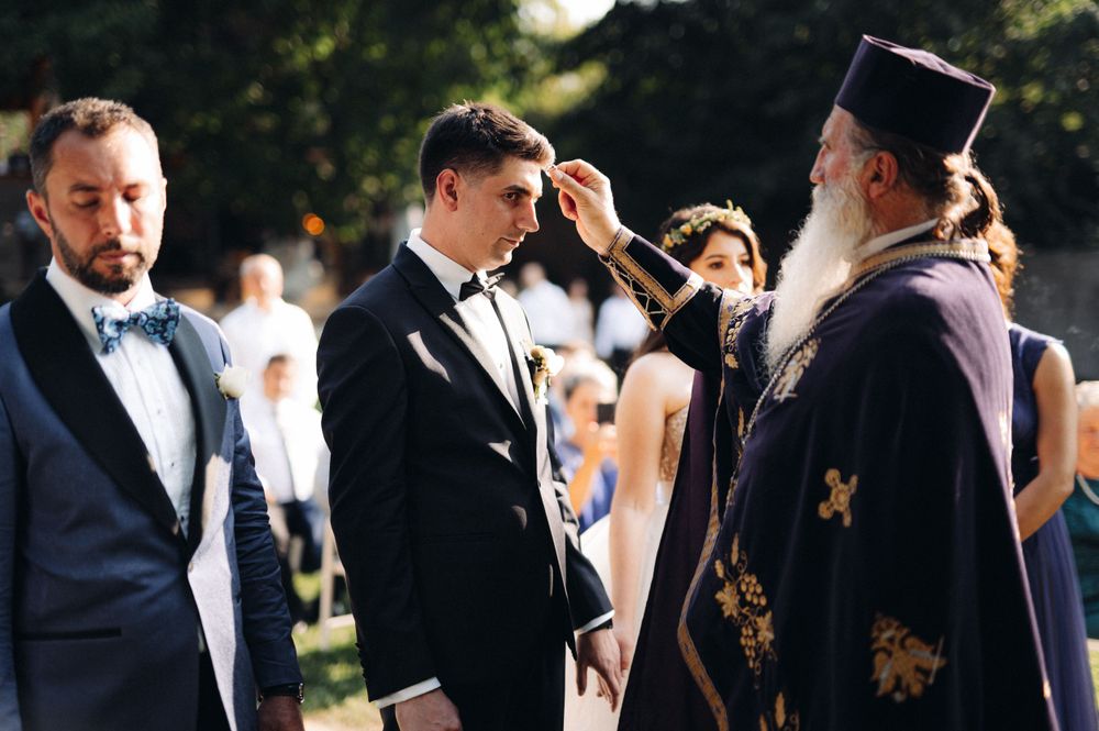 An Orthodox priest conducts a blessing during an outdoor wedding ceremony.