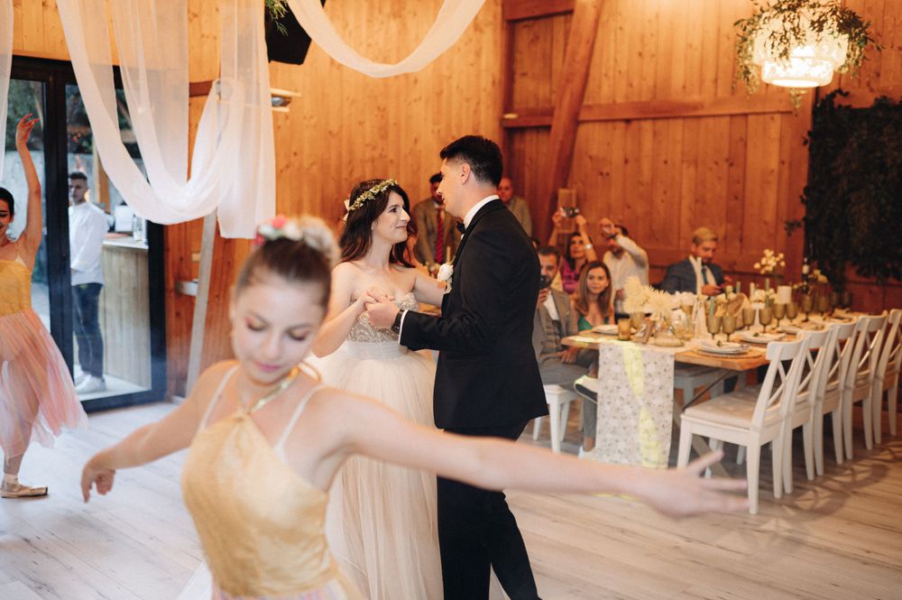 Dancers move gracefully across wooden dance floor at elegant reception with white draping decorations.