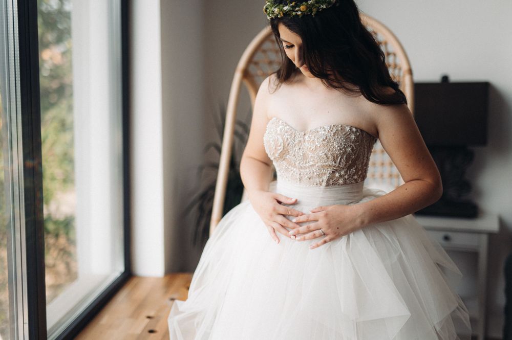 Ethereal bridal moment by window light showing intricate beaded bodice and flowing tulle skirt.