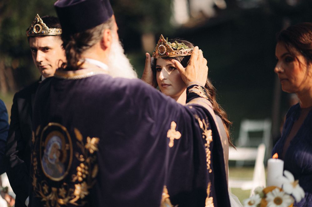 Wedding attendees wearing ceremonial crowns during an Orthodox Christian ceremony.