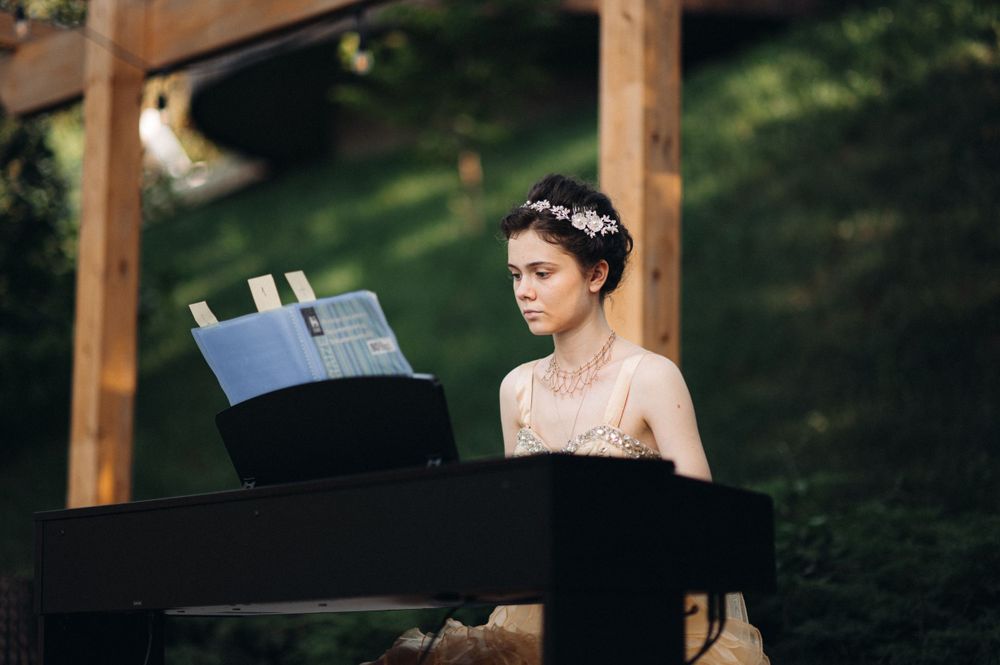 Musician performing on grand piano outdoors during elegant garden event.