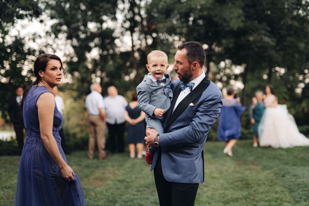 Wedding guests in formal attire gather on a lawn during an outdoor celebration.