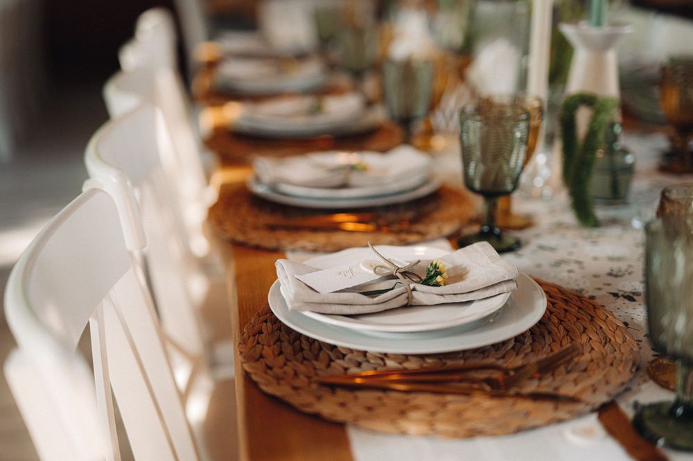 Elegant table setting with woven charger plates, white dinnerware and delicate place settings.