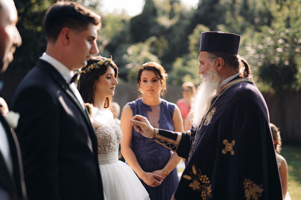 A traditional Orthodox wedding ceremony takes place in a garden setting.