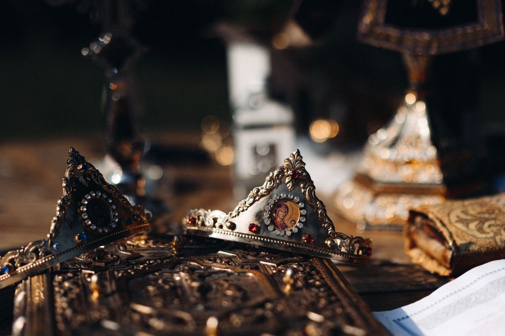 Close-up detail of ornate vintage crowns with dark metallic finish on white surface.