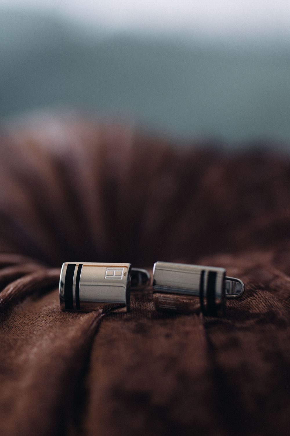 Two black metal camera lens parts resting on a brown textured surface with shallow depth of field.