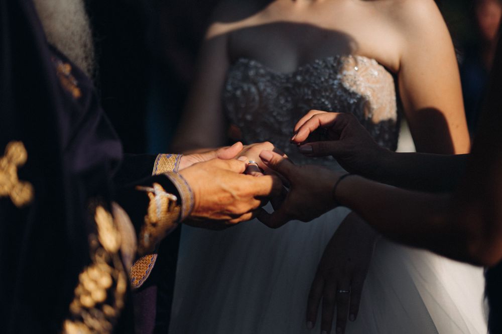 Close-up of hands exchanging rings during a wedding ceremony.
