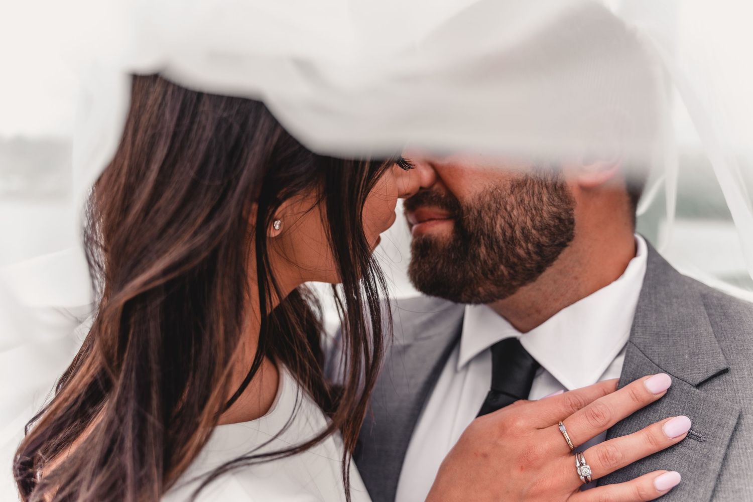 Intimate wedding portrait showing details of white veil and elegant jewelry.