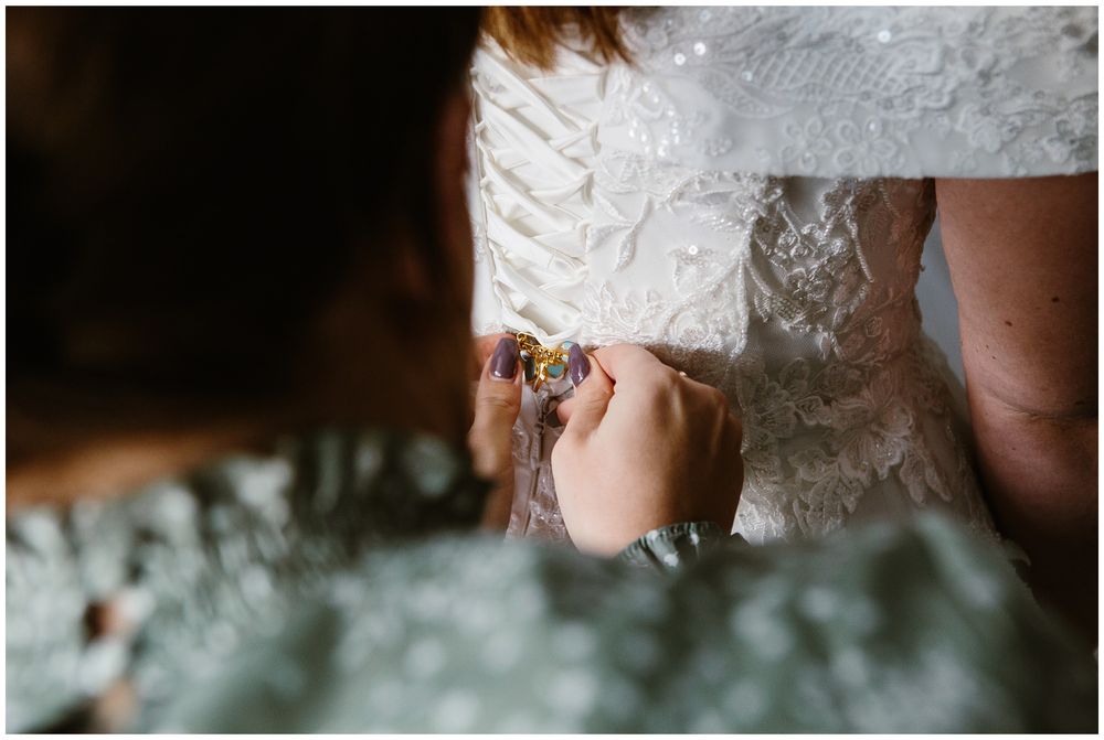 mom helping bride with dress