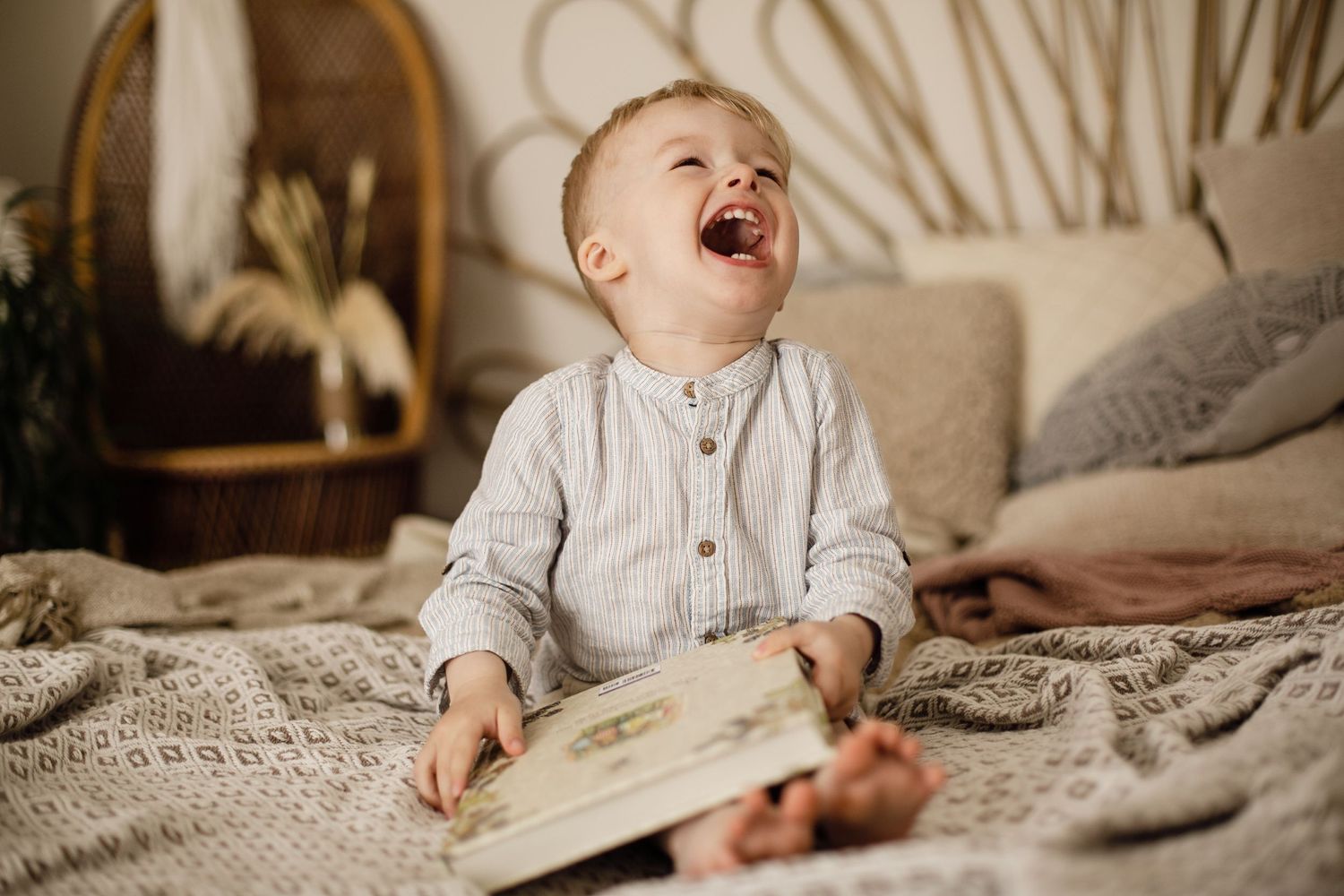 A little boy reading his book cracking up laughing. Lifestyle photography.