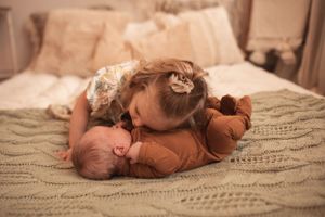 A sweet family scene on a knitted blanket with warm lighting and neutral tones.