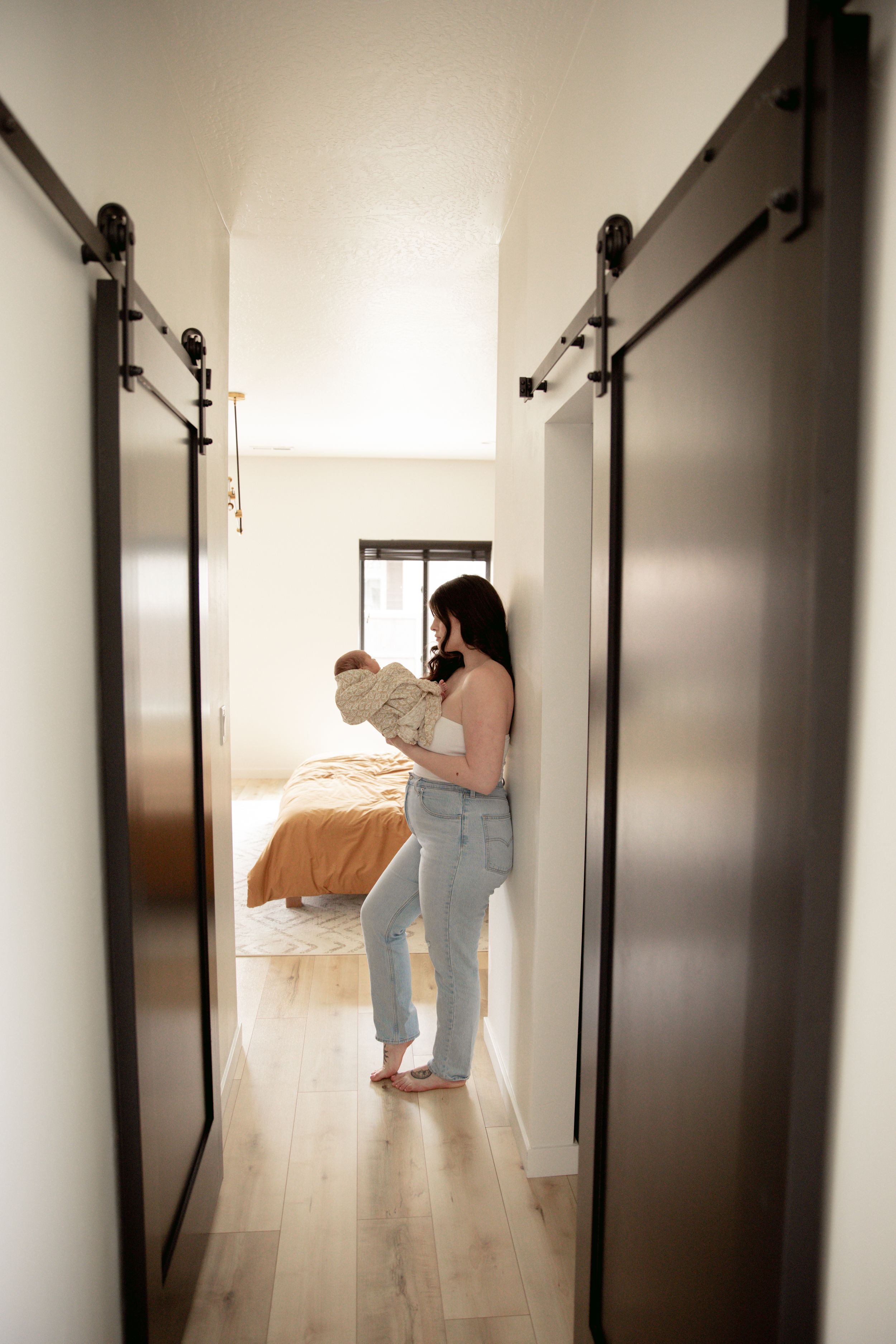 A person holding a baby while standing in a hallway with modern sliding barn doors.