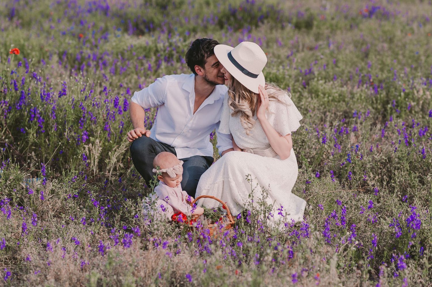 A picturesque scene in a field of purple wildflowers with figures in light colored clothing enjoying a sunny day.