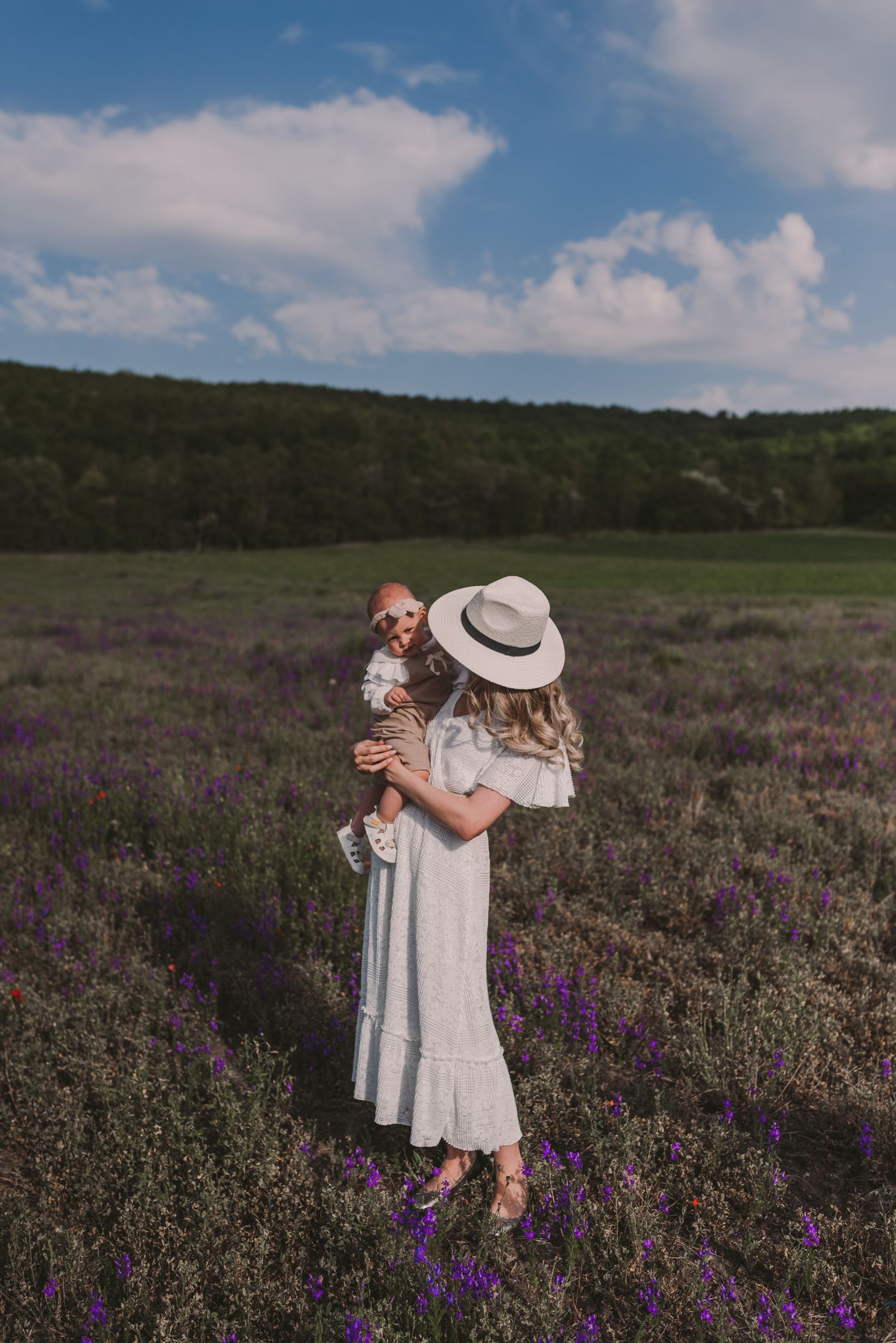 A touching moment captured in a vast field of purple wildflowers under a blue summer sky.