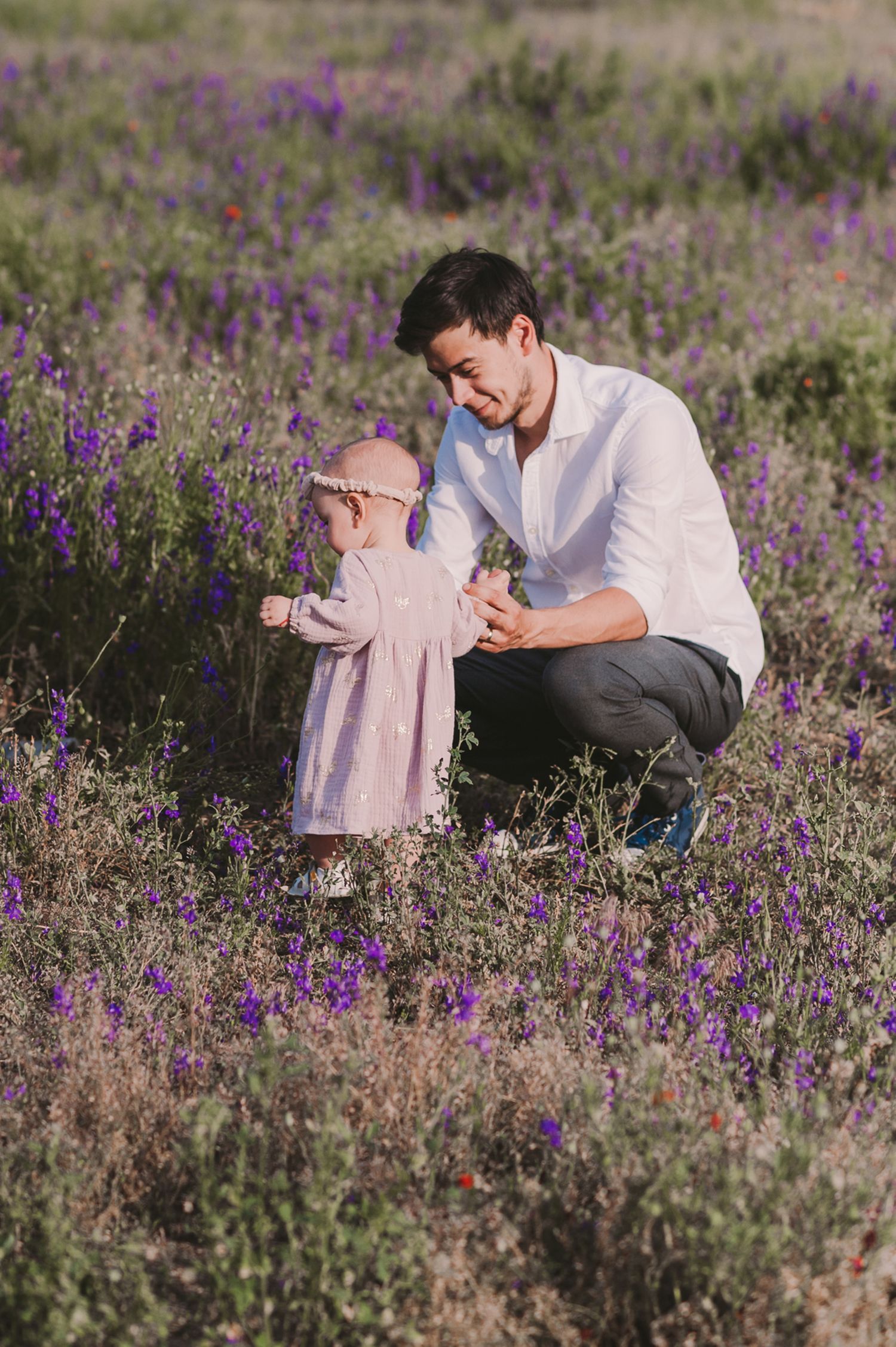 Family spending time together among purple wildflowers in a meadow.