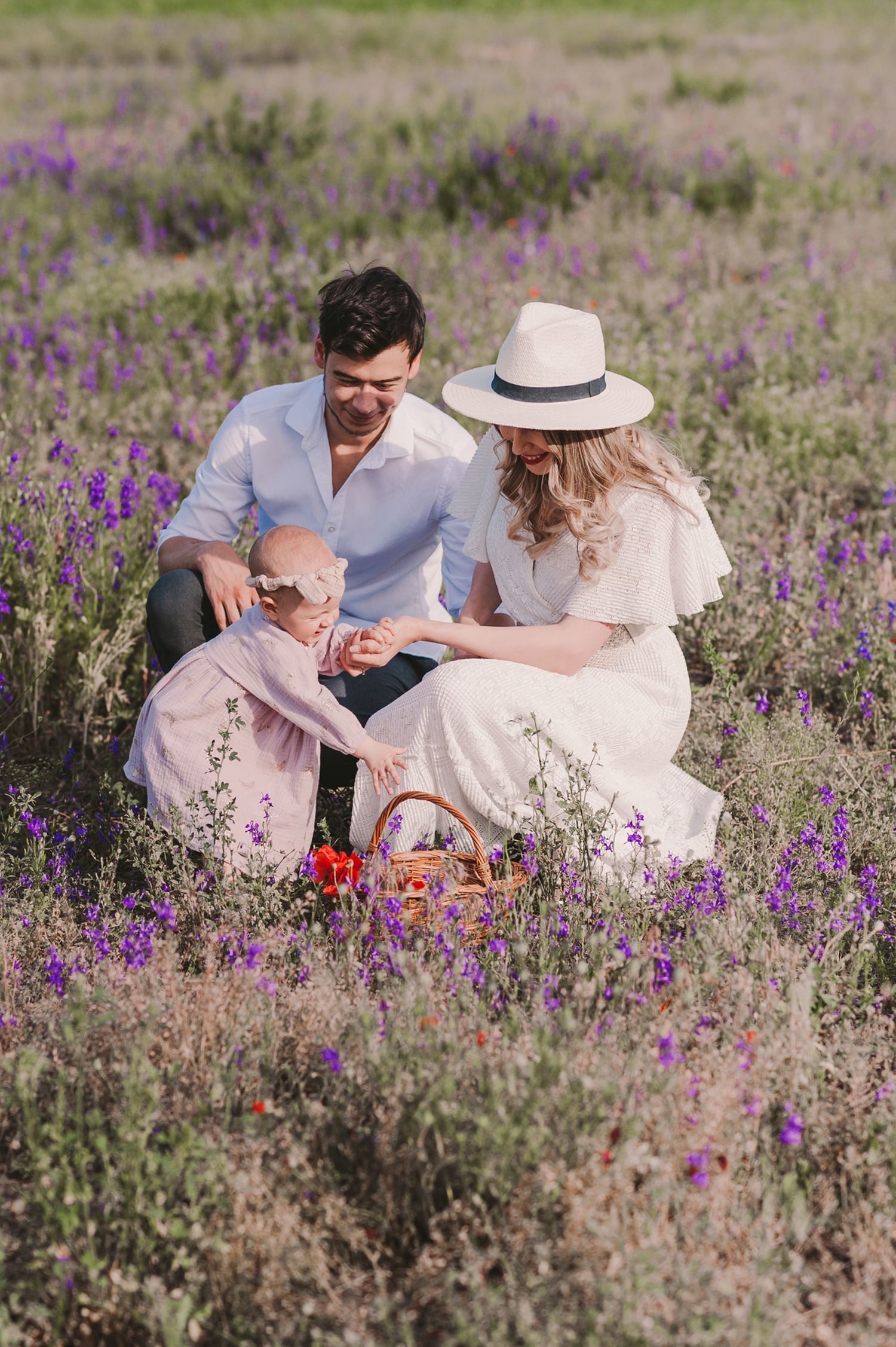 Family having picnic in meadow surrounded by purple wildflowers.