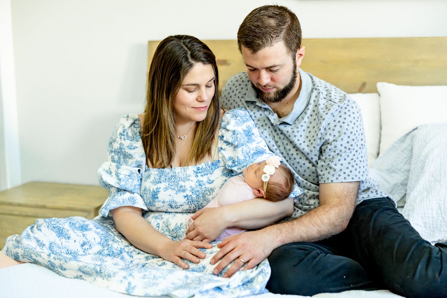 Parents snuggle on their bed holding and gazing at their baby girl during newborn photos in Colorado Springs.