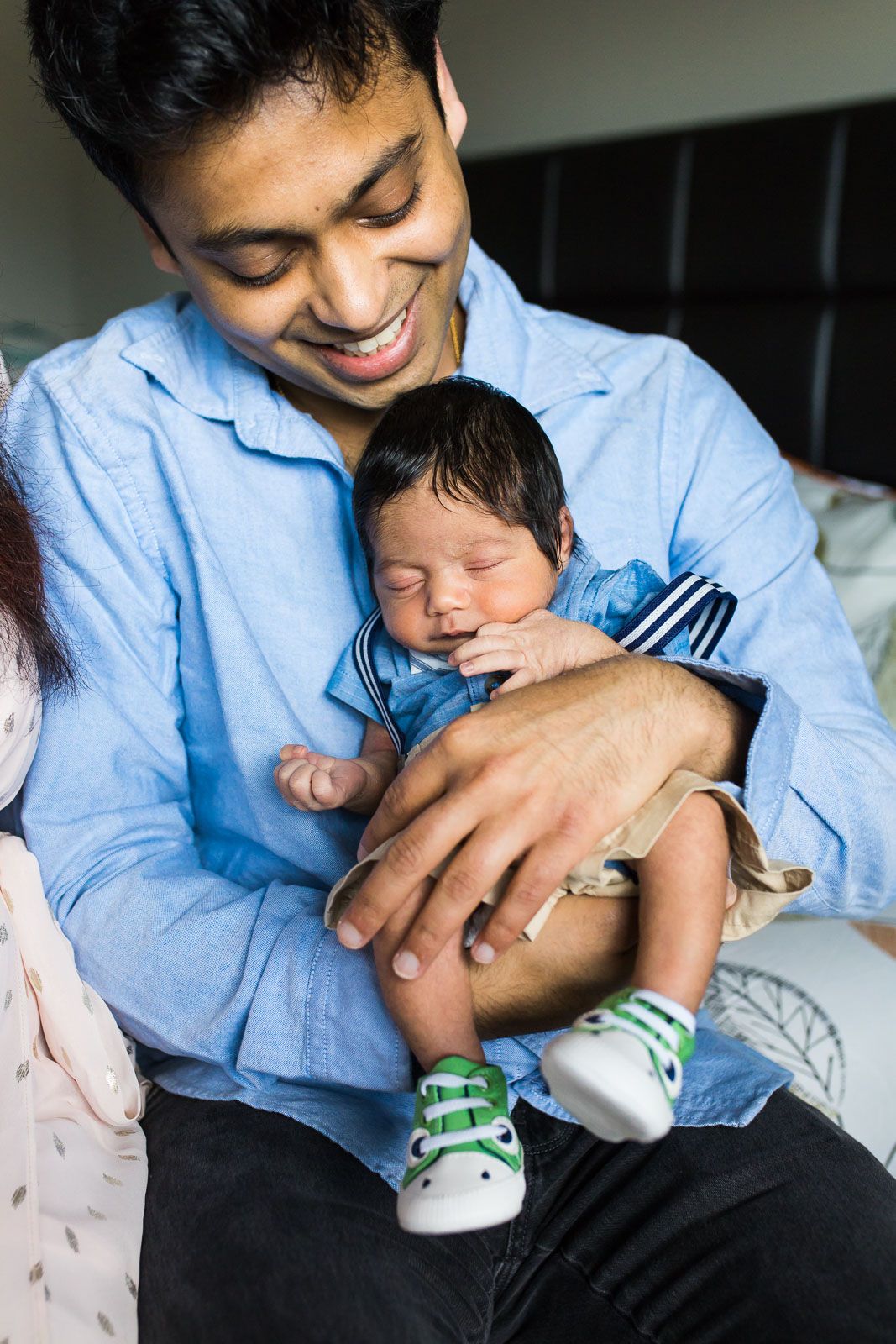 Father holding newborn son at his home