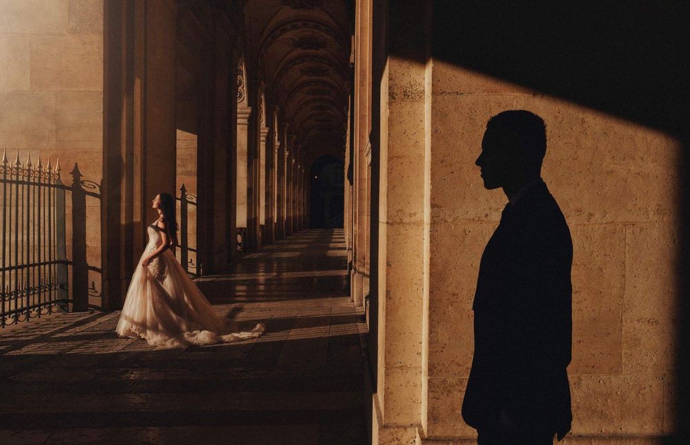 Silhouettes creating dramatic shadows in a grand hallway with stone architecture.
