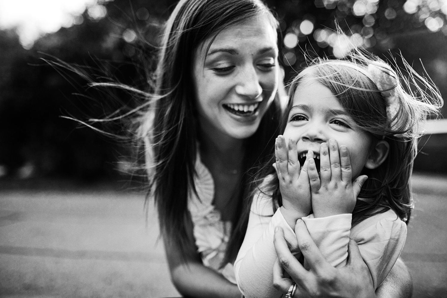 A joyful black and white candid moment of laughter and connection outdoors.