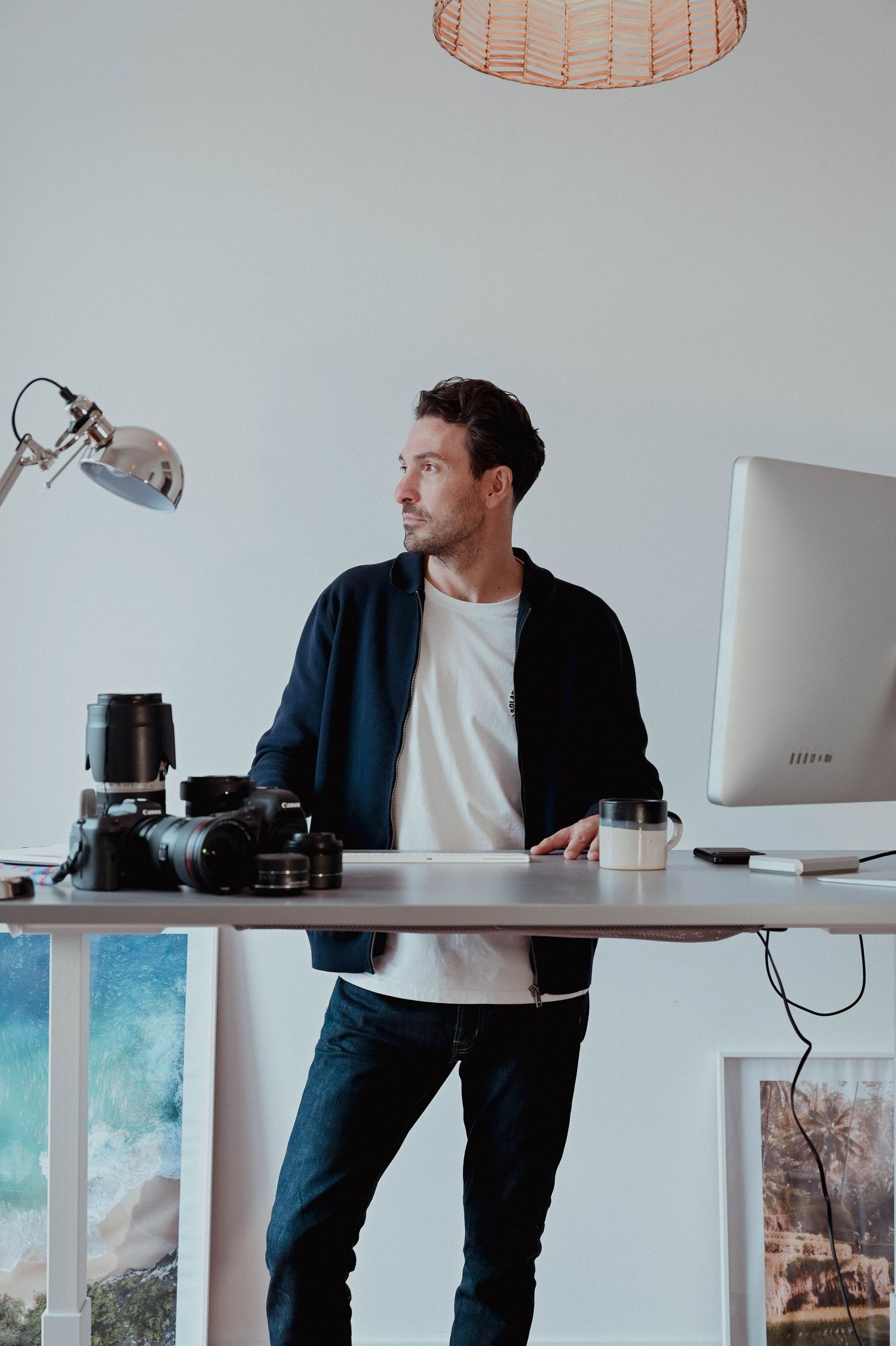 Creative workspace setup with desk, computer, camera equipment and modern lighting.