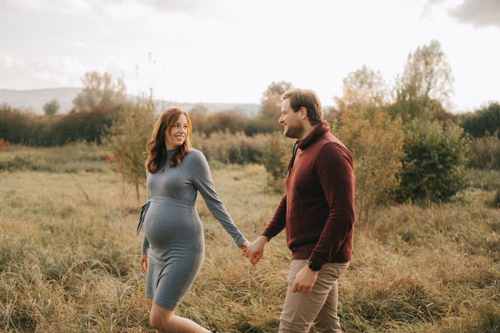 A couple shares a tender moment while walking through tall grass at sunset.