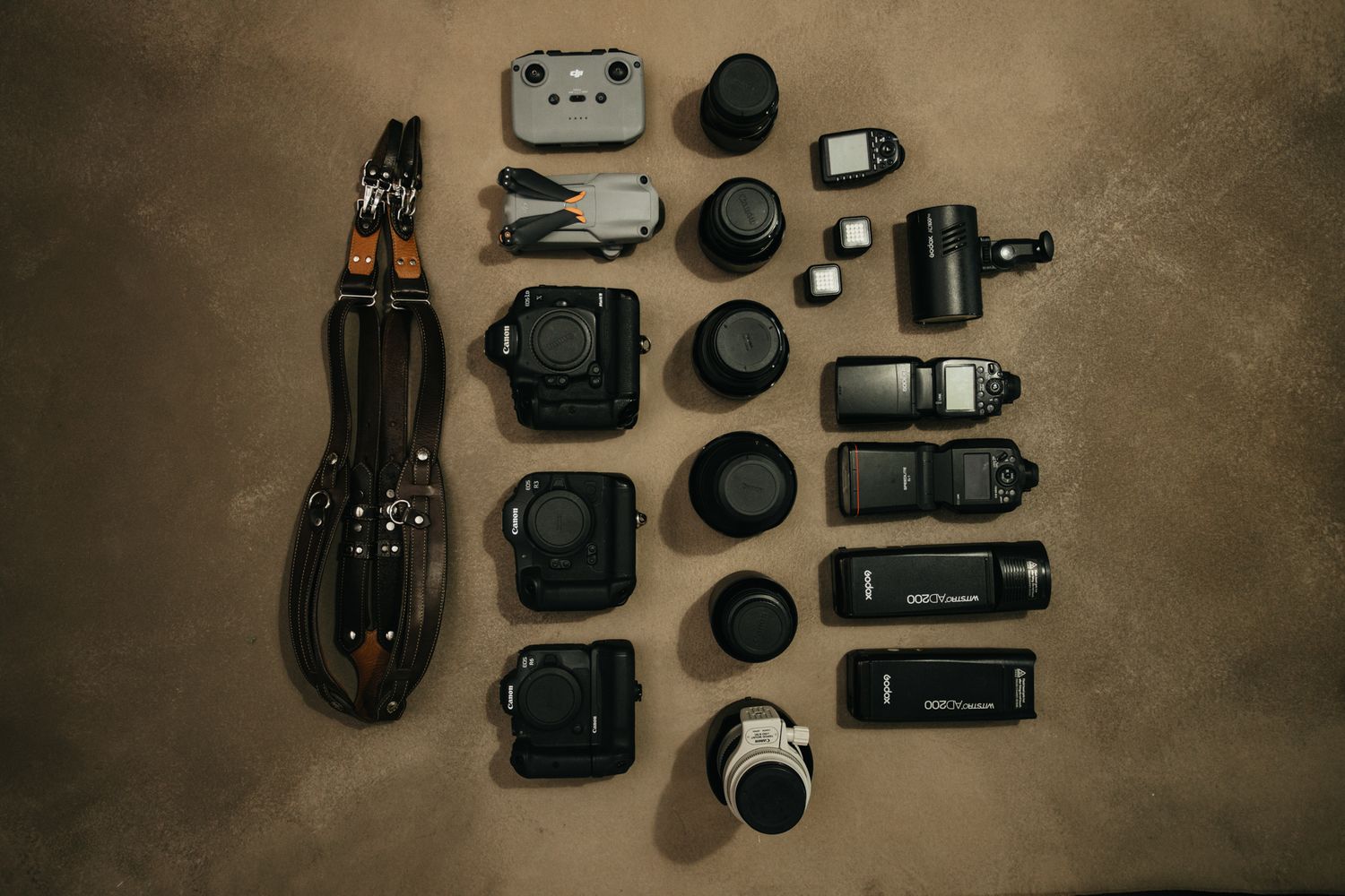 Flat lay of professional photography gear and equipment on brown textured background.