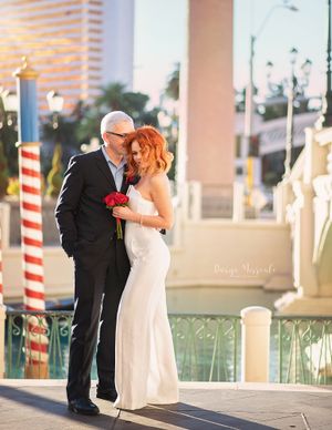 Wedding couple shares intimate moment on balcony with decorative columns and holiday decor.