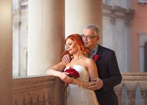 Romantic wedding portrait with couple embracing by classical architecture and columns.