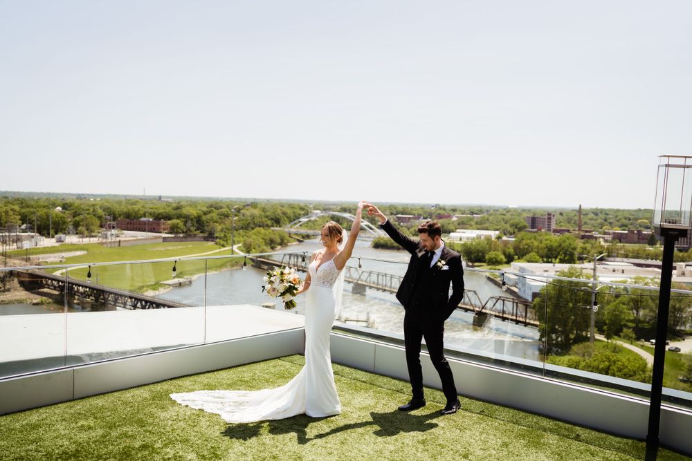 A wedding couple dances together on a rooftop with a scenic river view in the background.