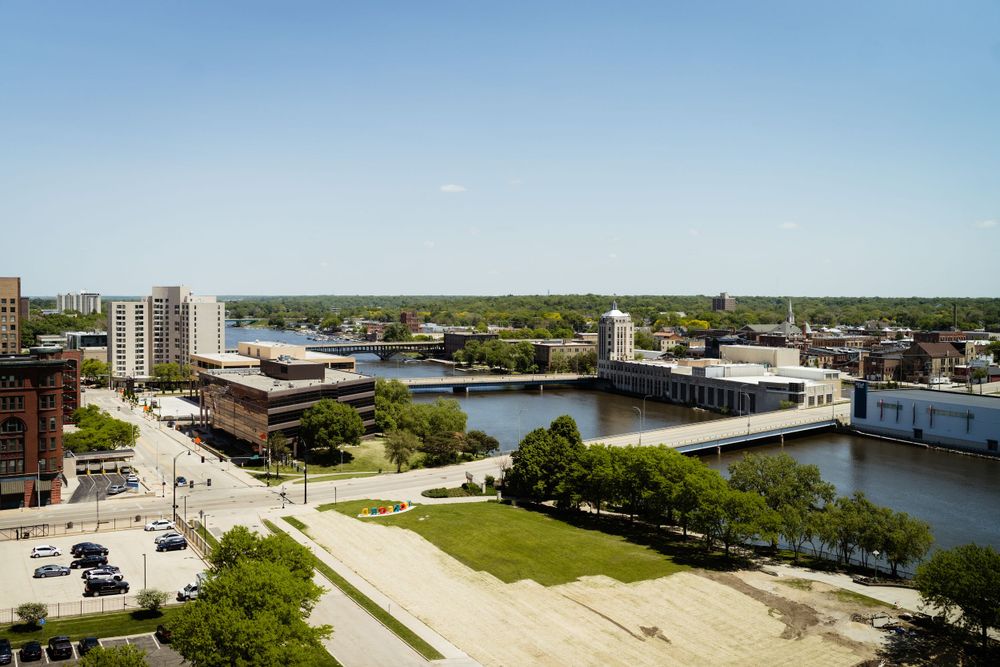 Aerial view of a cityscape with a river running through it and green spaces along the waterfront.