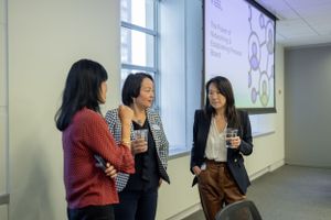 Casual business meeting with three people discussing near a presentation screen.