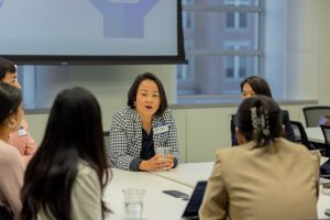 Professional discussion taking place around a conference table with presentation screen visible.