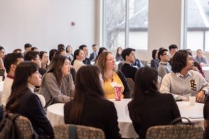 Large audience seated in rows at tables during a professional conference or seminar.