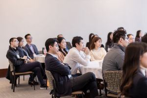 Attendees seated in rows listen attentively during a professional conference presentation.