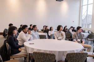Conference room with multiple attendees seated at tables during professional presentation.