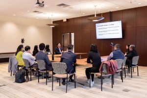 Business meeting attendees seated in classroom style arrangement during presentation.