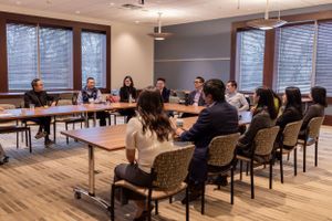 Professional meeting space with large windows and attendees seated in rows during presentation.