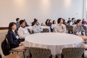 Conference attendees gathered at round tables in a meeting room with white tablecloths.