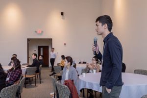 Side view of an indoor conference setup with attendees seated in rows.