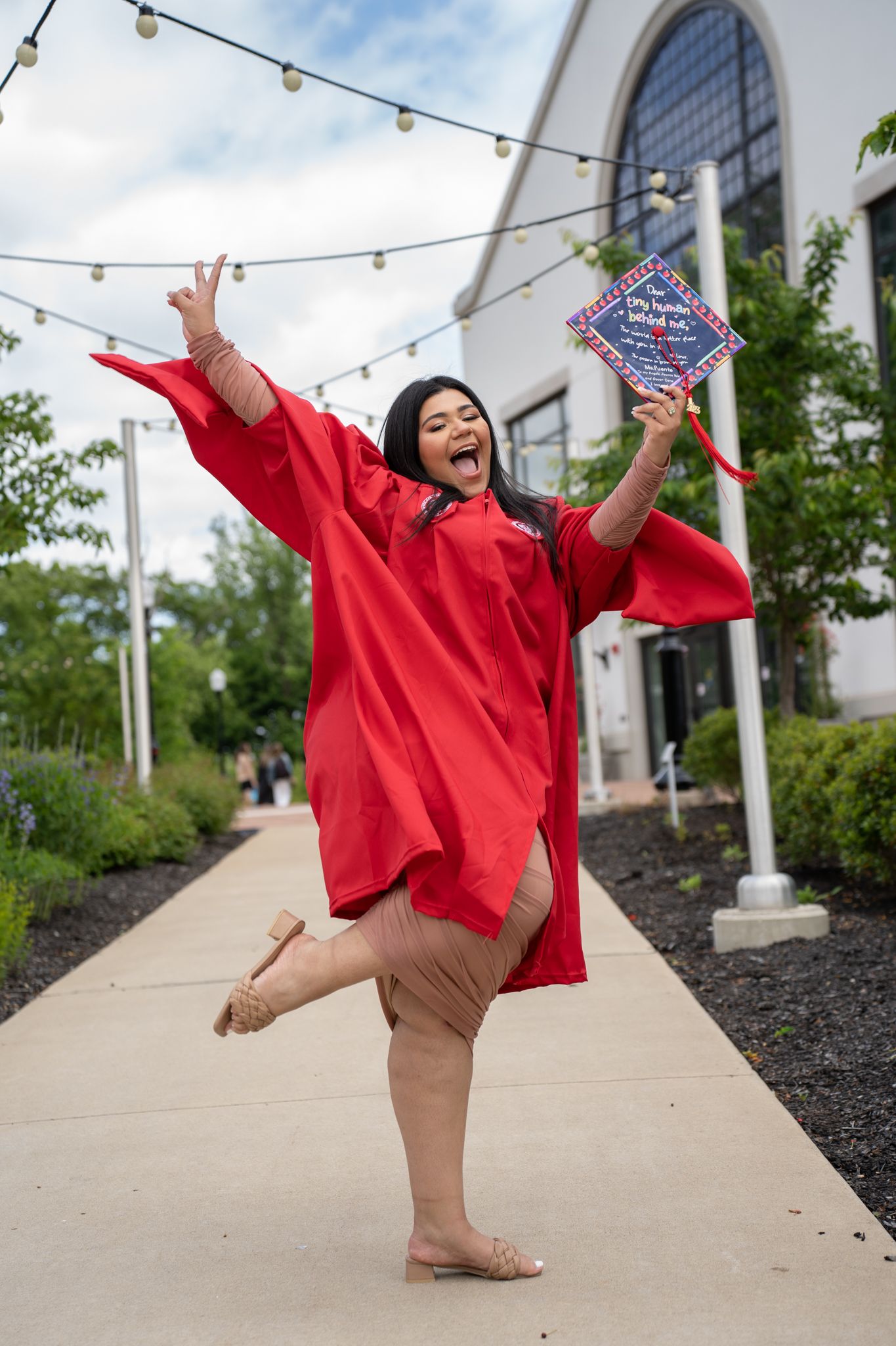 Celebratory graduation photos showing playful poses in red academic regalia outdoors.
