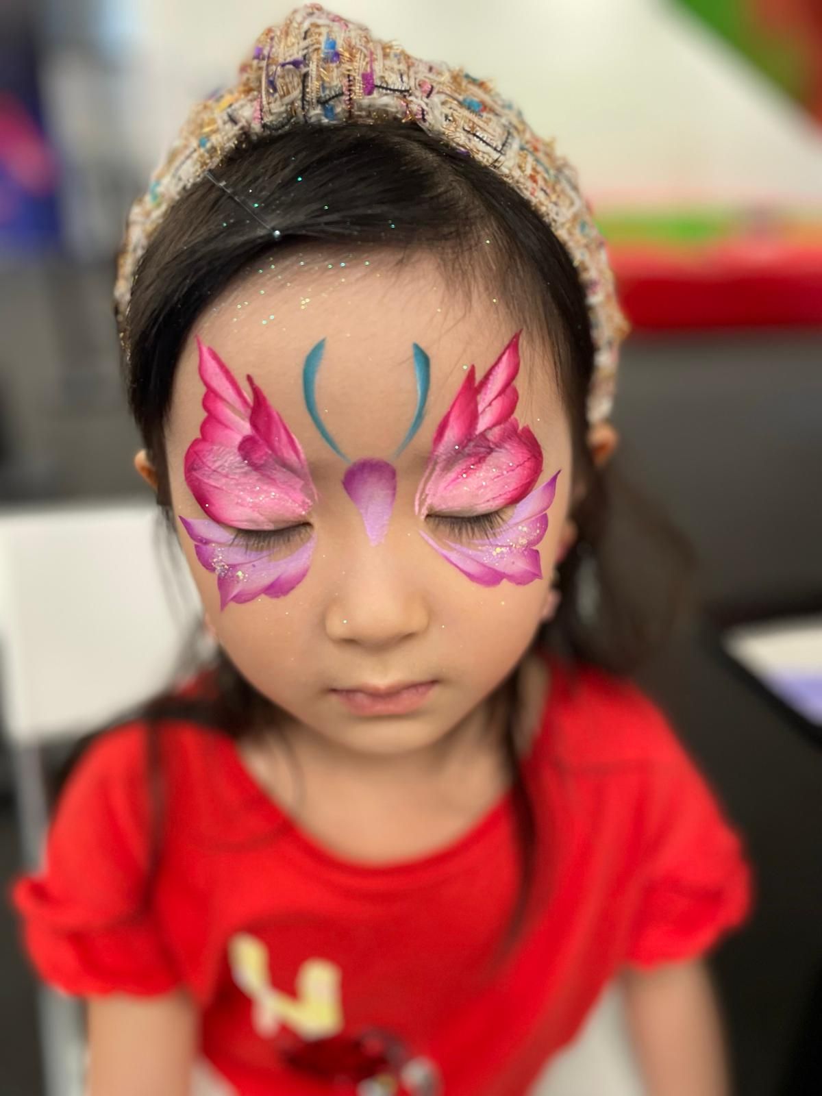 Pink butterfly wing face paint design with delicate details.