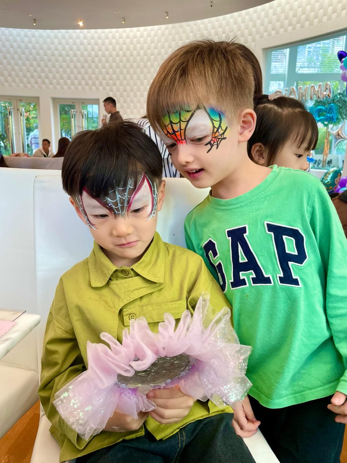 Face-painted children in casual clothes looking at something together.