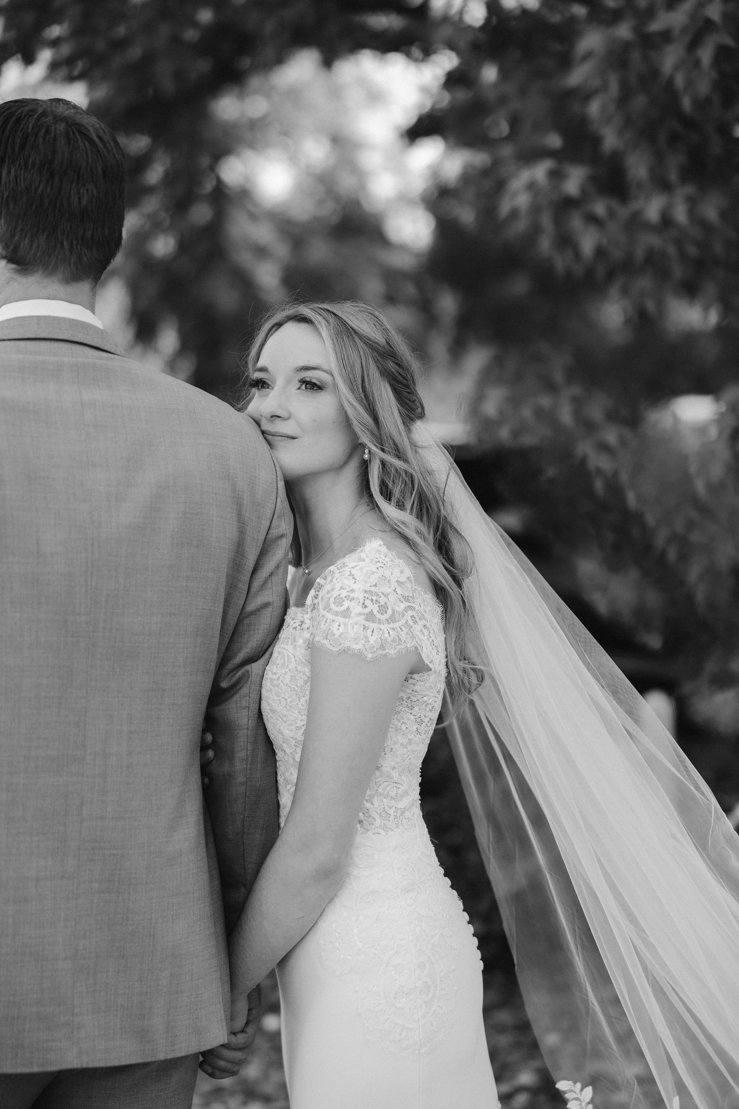 Black and white portrait of a bride looking over her shoulder with a flowing veil.