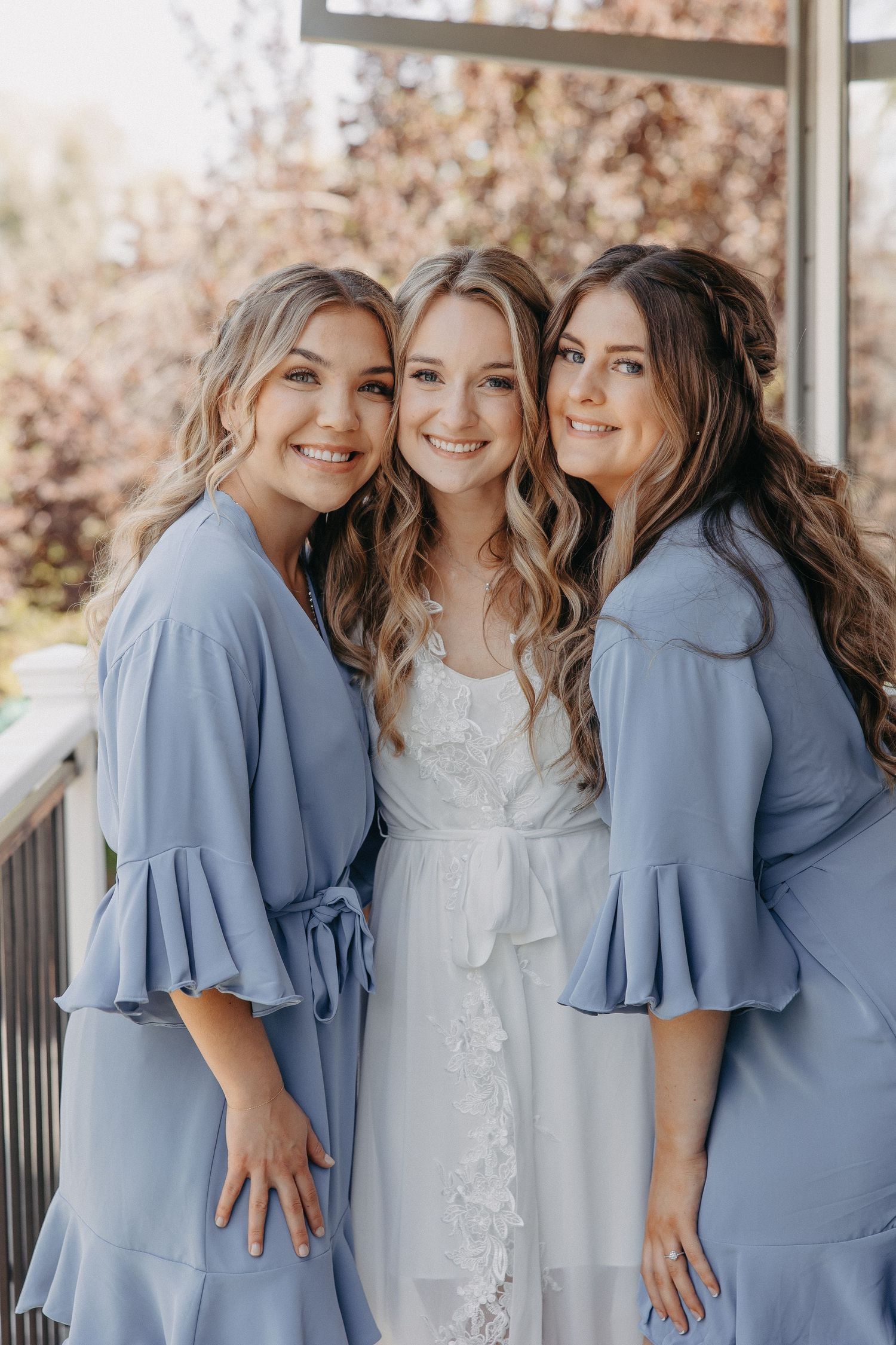Wedding party in powder blue dresses pose together on outdoor deck.